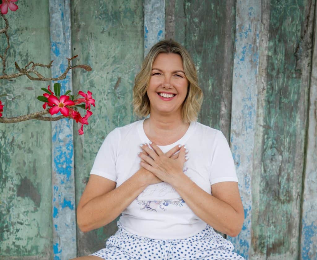 Kristina smiling with her hands on her heart, offering compassionate online life coaching