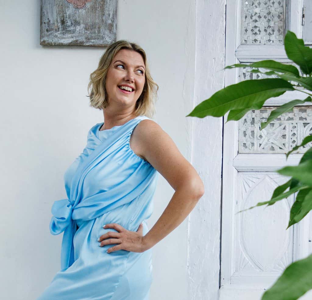 Kristina, certified holistic life coach, smiling happily in a natural outdoor setting, embodying the calm and groundedness she helps clients achieve